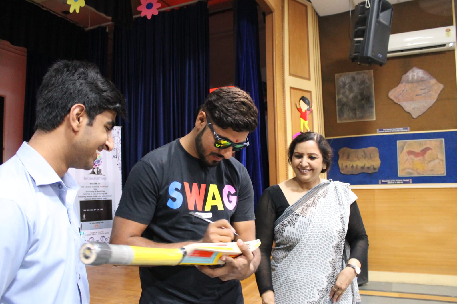 Deepak Malik signing a cricket bat at the event
